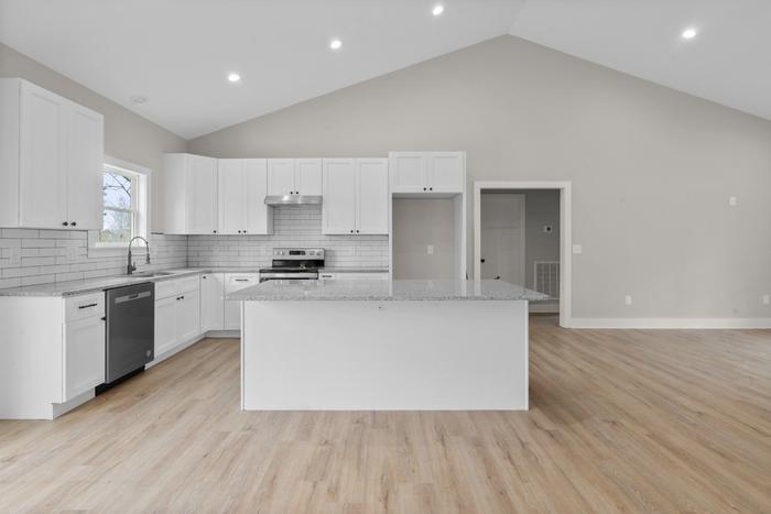 Kitchen with white cabinets, an island and a vaulted ceiling at the Lakeside Getaway home