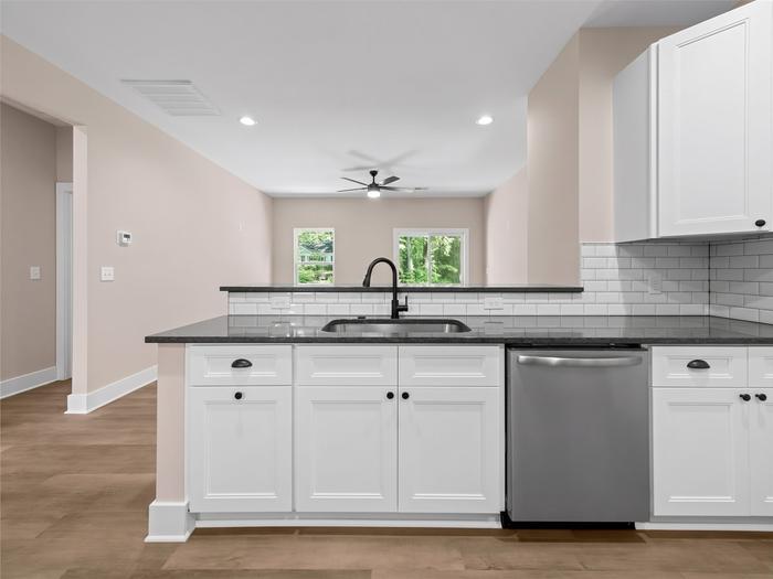 Kitchen with white shaker cabinets, subway tile and dark countertops