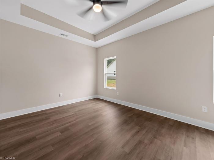 Primary bedroom with a tray ceiling and ceiling fan