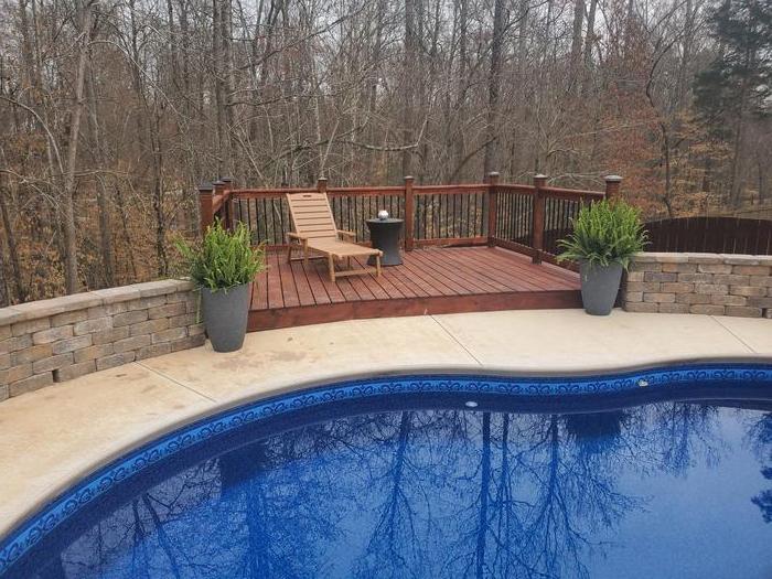 Pool with a stone retaining wall and raised wood deck