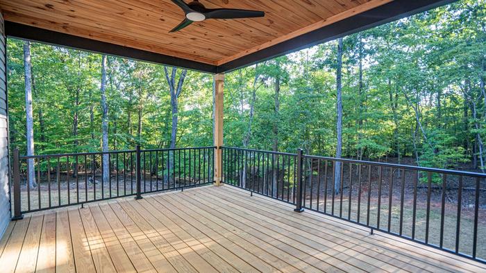 Covered back deck with a wood ceiling and ceiling fan overlooking the woods at Raven's Ridge