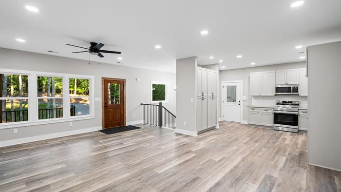 Great room with the front door, ceiling fan and open kitchen at Raven's Ridge